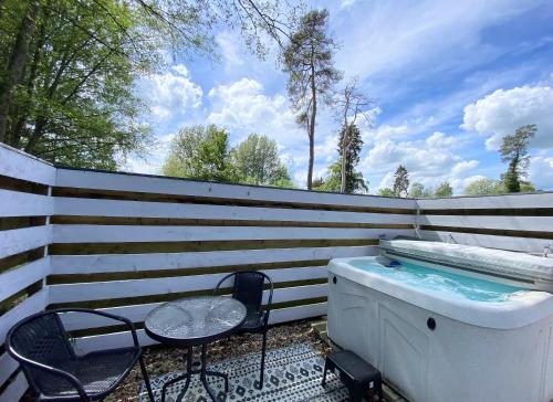 a hot tub and two chairs next to a fence at Magpie 6 HuntersMoon-Warminster-longleat-Bath in Warminster