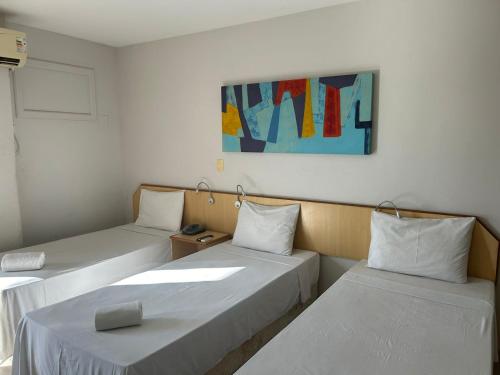 a room with two beds and a painting on the wall at IDEAL HOTELS in Macaé