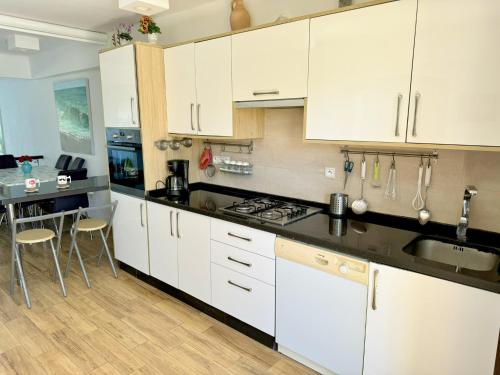 a kitchen with white cabinets and a sink and a table at Excelent Chalet Triplex in Kasr Rimal-Kabila Tetouan in M'diq