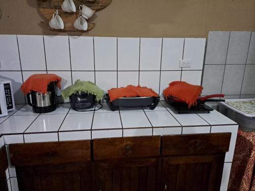 a kitchen counter with four pots with red covers on them at Hospedaje Beliz in Liberia