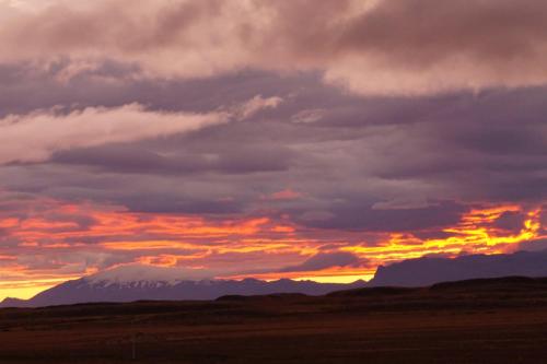 a sunset with a snow covered mountain in the distance at Hömluholt Holiday Homes in Hömluholt