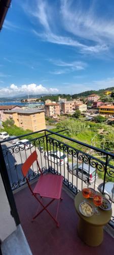 a red chair on a balcony with a view of a city at Moderno appartamento vista mare, con parcheggio privato in Portovenere
