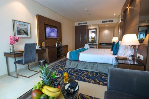 Cette chambre comprend un lit et une table avec des fruits. dans l'établissement Omega Hotel Dubai, à Dubaï