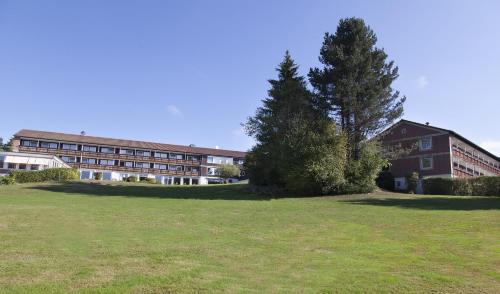 a large building with a tree in front of a field at Hotel Schwarzwald Freudenstadt in Freudenstadt