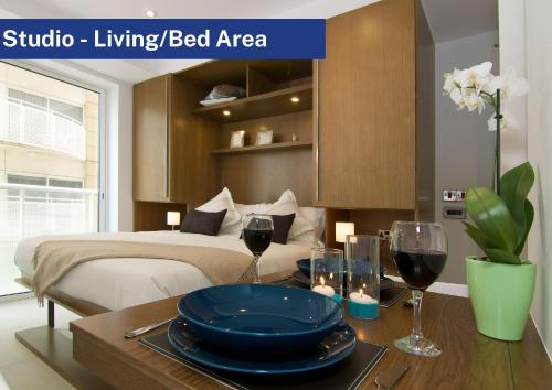 Bentley Holiday Apartments - West One في جبل طارق: غرفة نوم مع سرير وطاولة مع أكواب من النبيذ