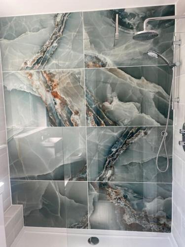 a bathroom with a shower and a marble wall at Bungalow on the beach in South Hayling