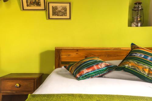 a yellow bedroom with a bed with two pillows at Hotel Casa Alquimia in Quito