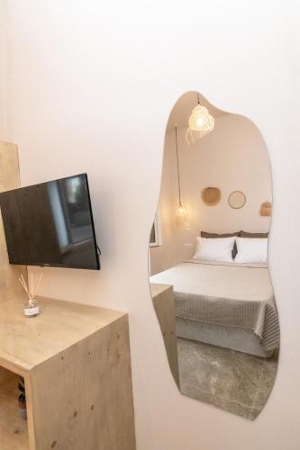 a mirror in a bedroom with a bed and a tv at armonia tinos in Tinos
