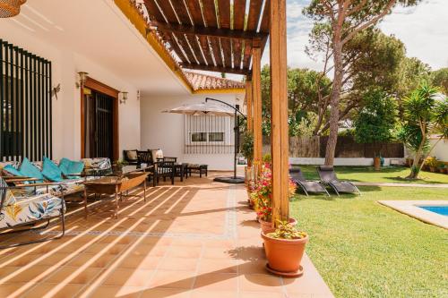 an outdoor patio with chairs and an umbrella at Precioso Chalet Atlántida solo familias in Roche