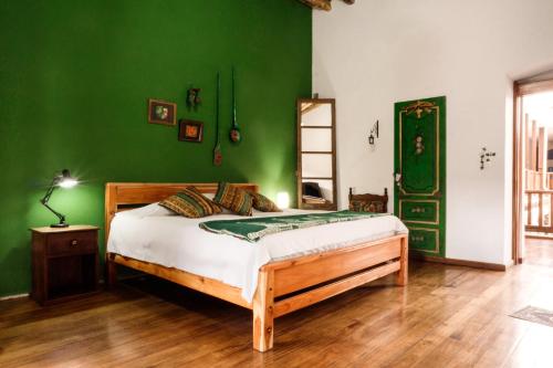 a bedroom with a bed with a green wall at Hotel Casa Alquimia in Quito
