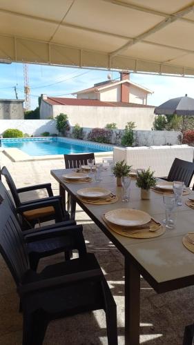 a table with plates and glasses and chairs and a pool at GuestReady - Casa do Farol in Marinhas