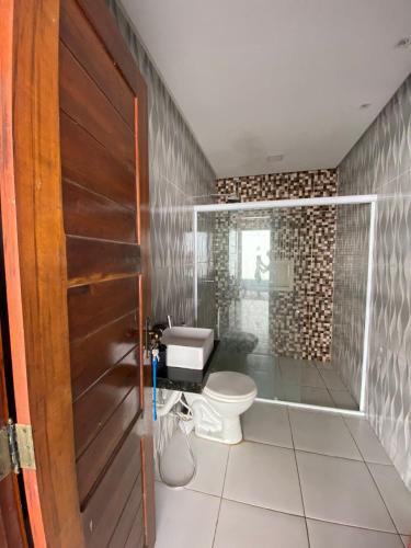 a bathroom with a toilet and a glass shower at Nosso Sítio in Camocim