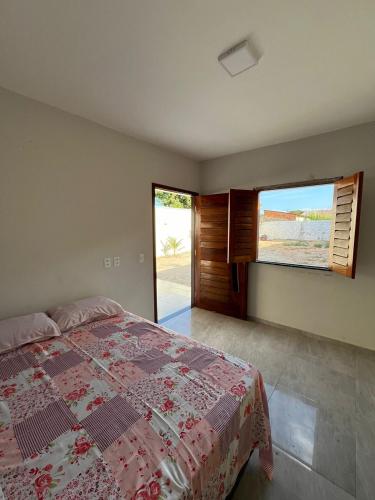 a bedroom with a bed and a large window at Nosso Sítio in Camocim