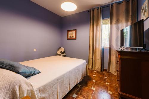 a bedroom with a bed and a flat screen tv at Precioso Chalet Atlántida solo familias in Roche