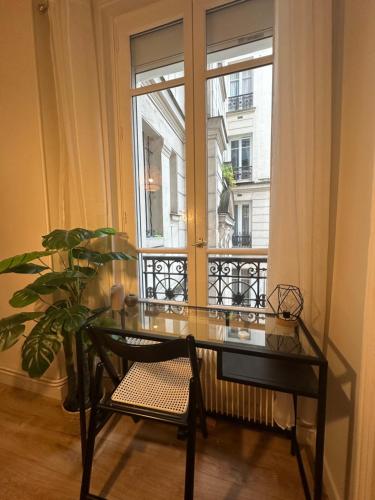 une table en verre et une chaise devant une fenêtre dans l'établissement Apparemment au bord de Paris, à Levallois-Perret