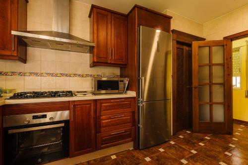 a kitchen with wooden cabinets and a stainless steel refrigerator at Precioso Chalet Atlántida solo familias in Roche