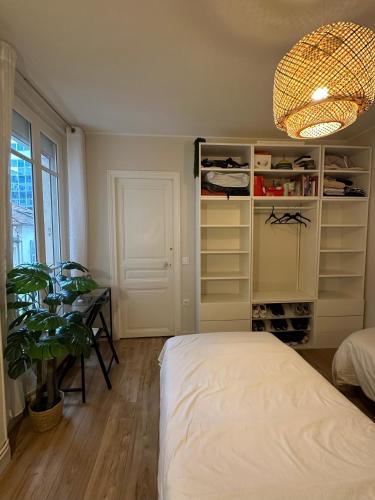 - une chambre avec un lit, une table et une plante dans l'établissement Apparemment au bord de Paris, à Levallois-Perret