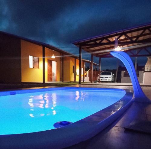 Chalés la belle de jour في Serra de São Bento: مسبح في الليل مع زحليقة المسبح الأزرق