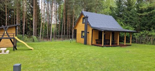 a small house in a yard with a playground at Leśne Zacisze 3 in Łuka