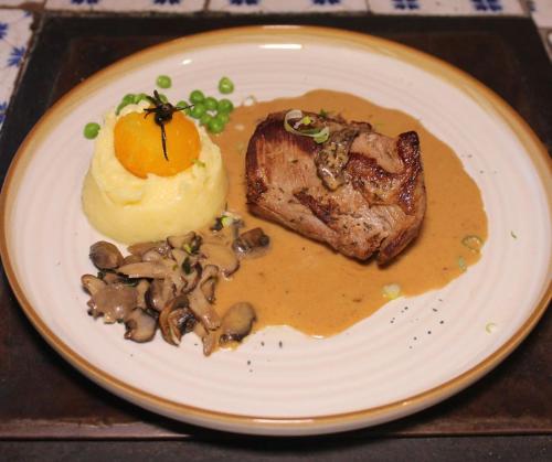 a plate of food with a piece of meat and mushrooms at La Maison TATIN in Lamotte-Beuvron