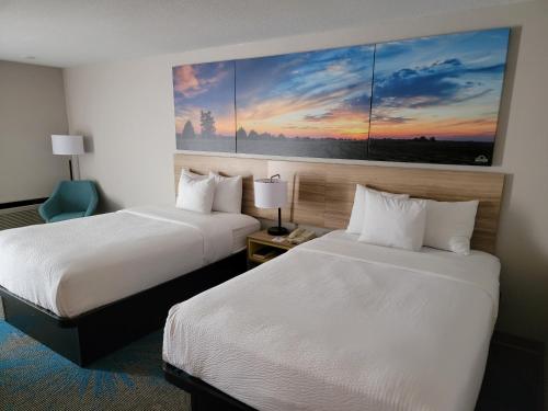 DoniphanにあるDays Inn by Wyndham Grand Island I-80のベッド2台が備わる客室で、壁には絵画が飾られています。