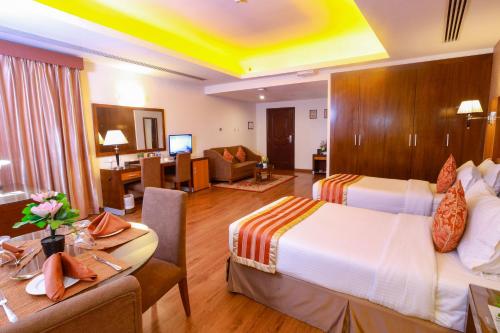 um quarto de hotel com duas camas e uma sala de estar em Fortune Pearl Hotel em Dubai