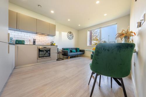 a kitchen and living room with a green chair at Luxury 1 Bedroom serviced apartment with Roof terrace & Gym in Stevenage