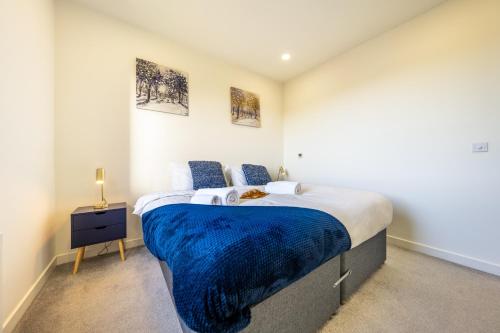 um quarto com uma cama grande e um cobertor azul em Luxury 1 Bedroom serviced apartment with Roof terrace & Gym em Stevenage