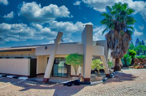 a building with a palm tree in front of it at Riverstone Guest Lodge in Harare