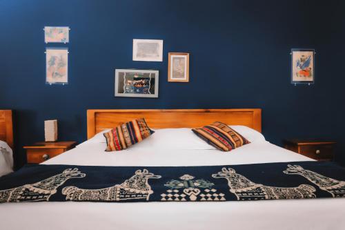 a bedroom with a bed with a blue wall at Hotel Casa Alquimia in Quito
