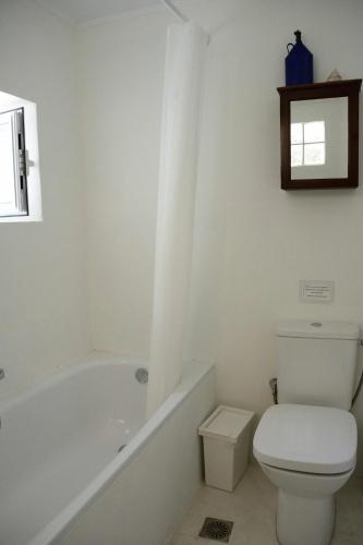 a white bathroom with a toilet and a bath tub at Metropolis Villa in Vathi, Ithaka