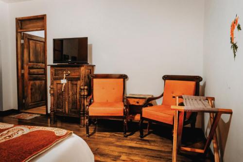 a bedroom with two chairs and a tv and a bed at Hotel Casa Alquimia in Quito