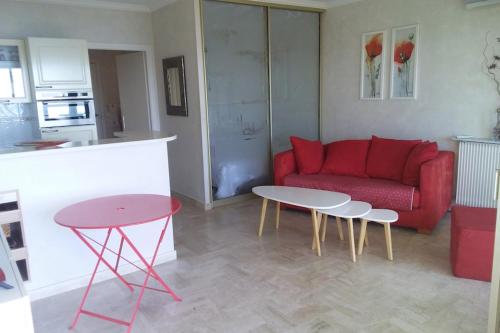 a living room with a red couch and a table at Cozy cocoon with balcony close to the sea in Cannes