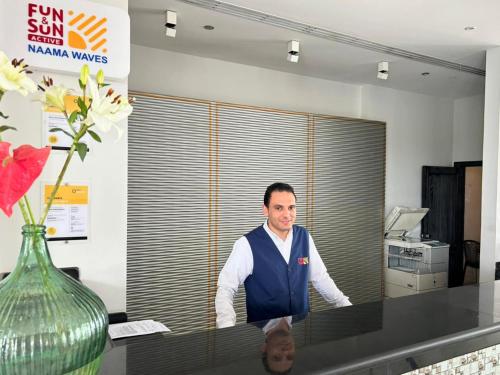 a man standing behind a counter in an office at Fun & Sun Naama Waves in Sharm El Sheikh