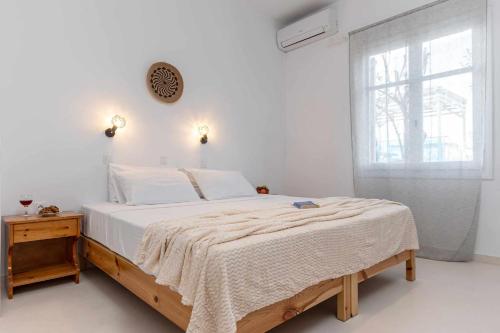 a white bedroom with a large bed and a window at Naxos Beachwalk Rooms in Naxos Chora