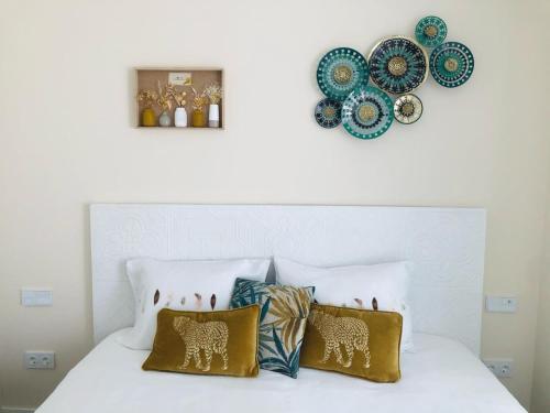 a white bed with pillows and plates on the wall at Luxury Apartment Diego - The View Fuengirola in Fuengirola