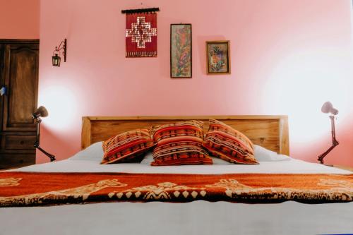 a bedroom with a bed with red and orange pillows at Hotel Casa Alquimia in Quito
