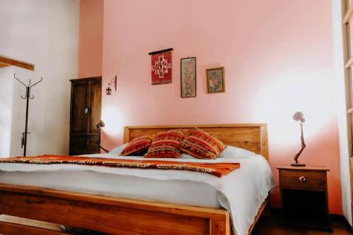 a bedroom with a wooden bed with red pillows at Hotel Casa Alquimia in Quito