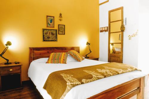 a bedroom with a white bed and a yellow wall at Hotel Casa Alquimia in Quito