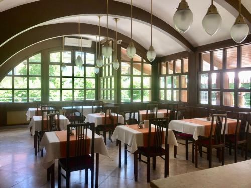 - une salle à manger avec des tables, des chaises et des fenêtres dans l'établissement Park Hotel Hévíz, à Hévíz