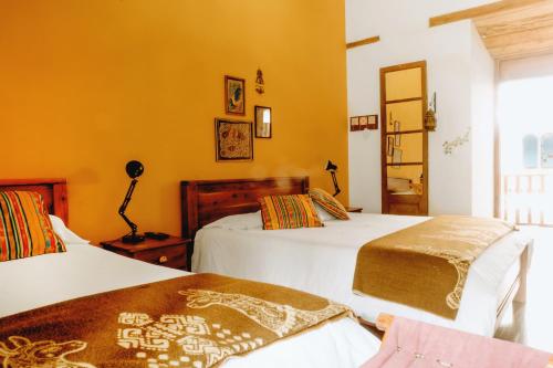 two beds in a room with yellow walls at Hotel Casa Alquimia in Quito