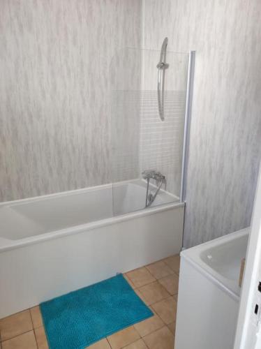 La salle de bains est pourvue d'une baignoire blanche et d'un tapis bleu. dans l'établissement appartement 80 m de la plage le Barcarès village, au Barcarès