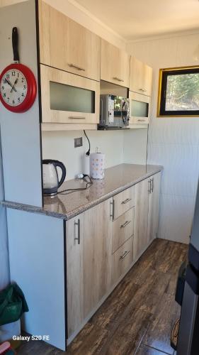 a kitchen with wooden cabinets and a red clock at Cabañas en el campo in Navidad