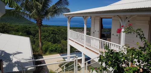 a white house with a balcony and a palm tree at REVE BLEU - Villa classée 4* vue mer - 6 pers in Deshaies