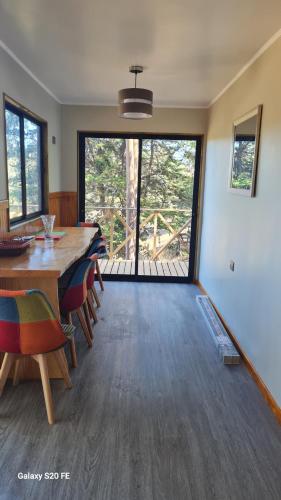 a dining room with a table and chairs and a large window at Cabañas en el campo in Navidad