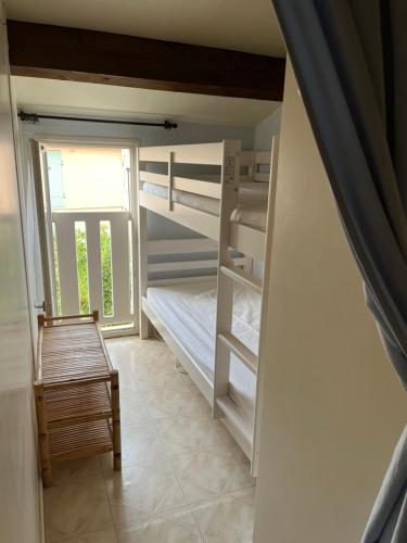 Cette chambre dispose de lits superposés, d'une chaise et d'une fenêtre. dans l'établissement Maison T2 + cabine dans résidence avec piscine, à Marseillan
