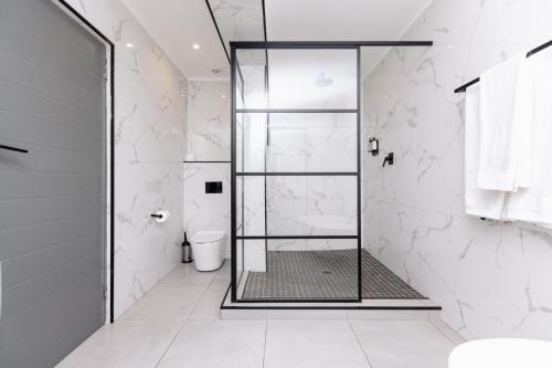 a shower with a glass door in a white bathroom at MINT Hotel 84 on Katherine in Johannesburg
