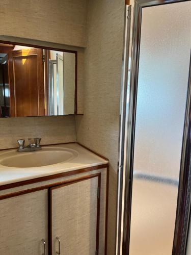 Un baño con lavabo, espejo y nevera. en Yacht Moineau VI, en Deauville