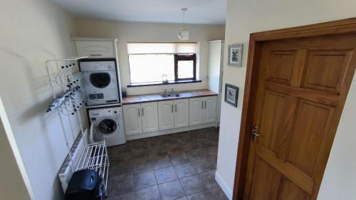 uma cozinha com uma máquina de lavar roupa, um lavatório e uma porta em Swinford Country House em Swinford