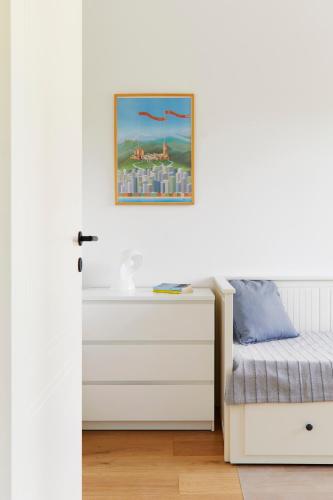 a white bedroom with a bed and a dresser at La Sismonda in Rimini